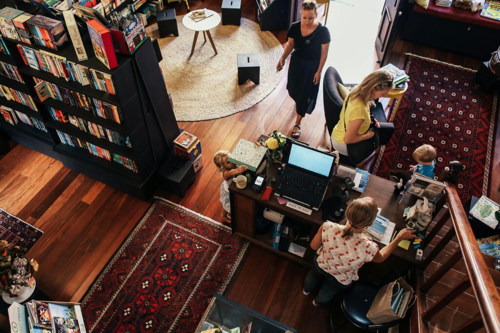 A vibrant bookstore scene with people browsing and interacting, showcasing bookshelves and unique rugs.